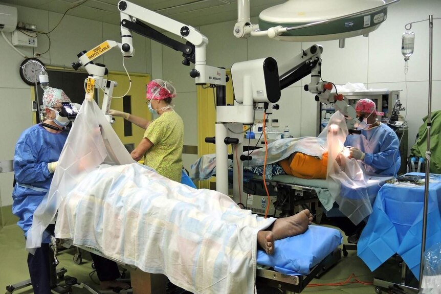 Surgeons and medical support staff in an operating theatre.