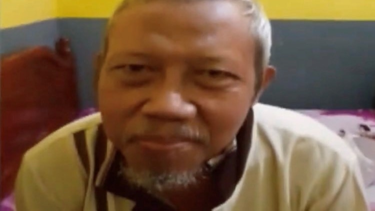 A man with grey hair, beard and moustache looks at the camera.