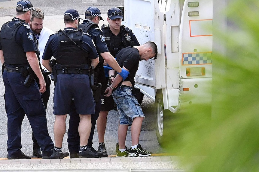 Man being taken into the back of the police wagon by police.