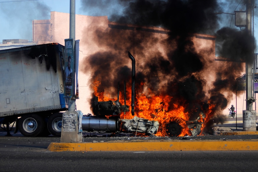A truck burns with black smoke and high flames on a street in Culiacan.