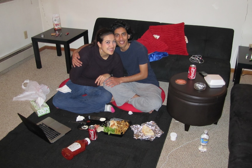 A couple have dinner next to the couch.