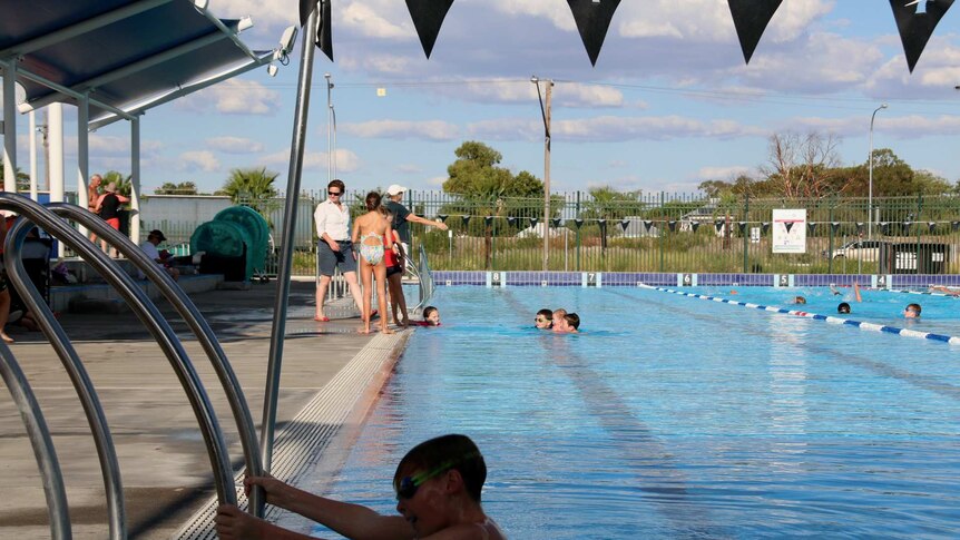 A boy climbs out of swimming pool in Moree, NSW