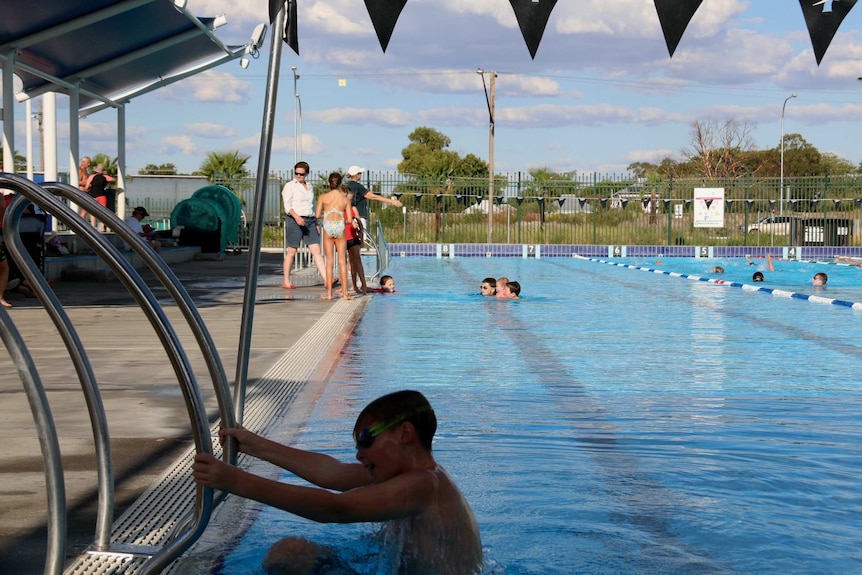 A boy climbs out of swimming pool in Moree, NSW