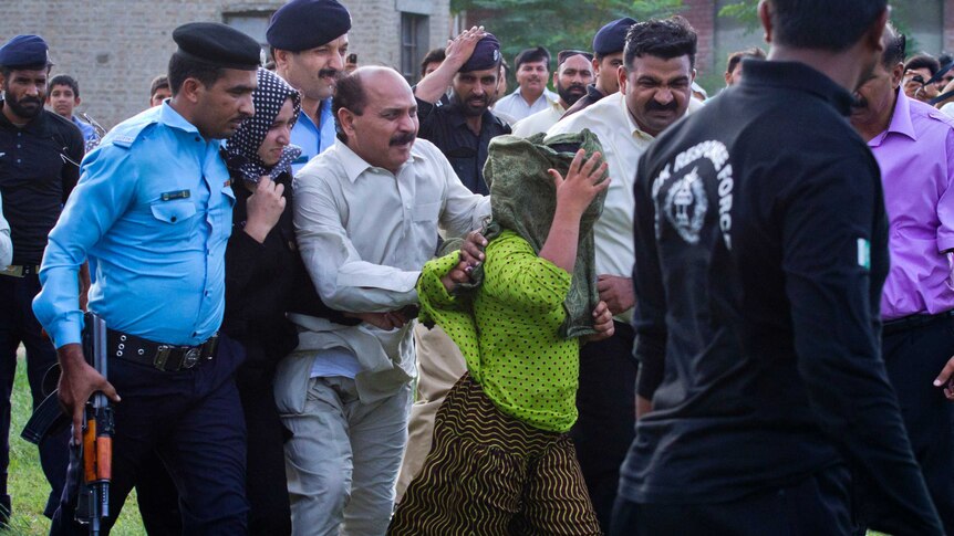 Security officials surrounding a Christian girl accused of blasphemy, move her to a helicopter in Rawalpindi