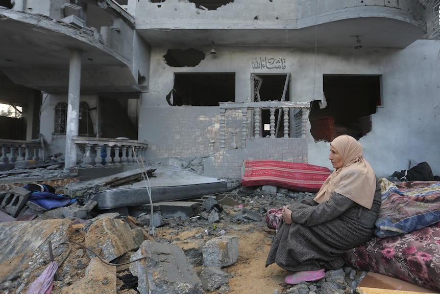 A Palestinian woman sits by houses destroyed in the Israeli bombardment of the Gaza Strip.