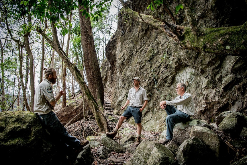 Three men sit on rocks.