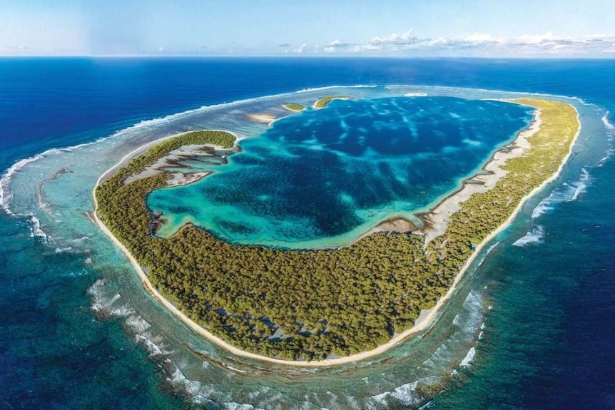 An aerial shot of an island with an atoll at its centre.