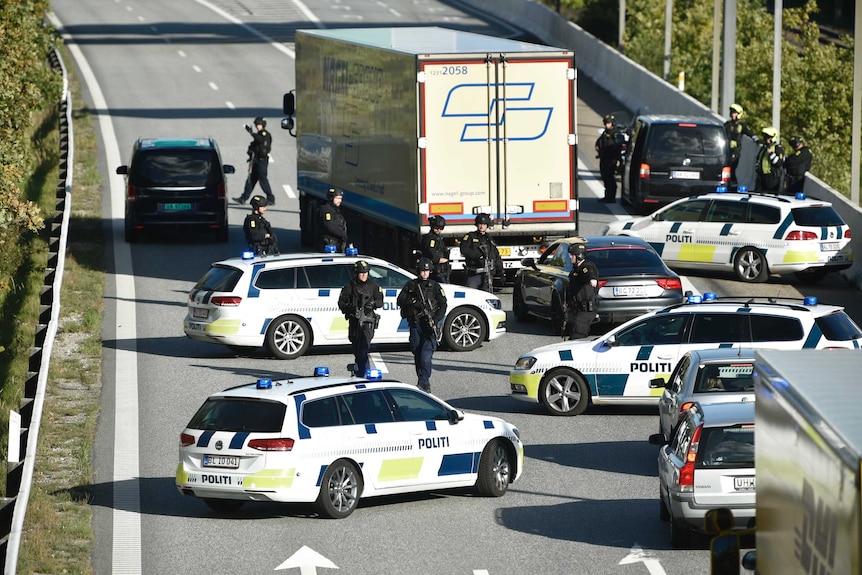 Danish police vehicles line up across a bridge blocking the road