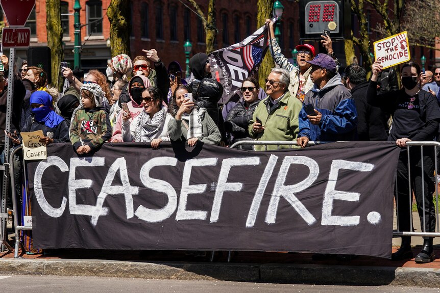A group of protesters stand behind a 'ceasefire' sign 