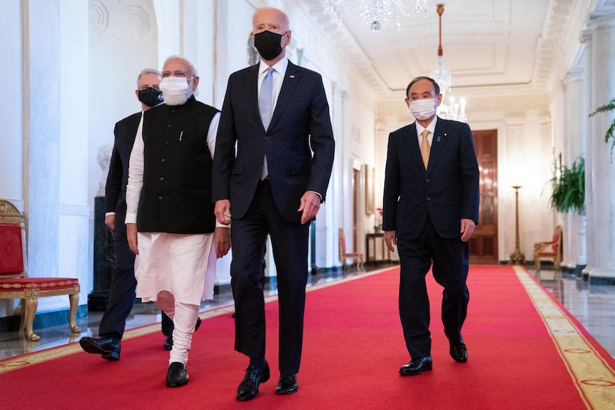 four men walking down a hallway