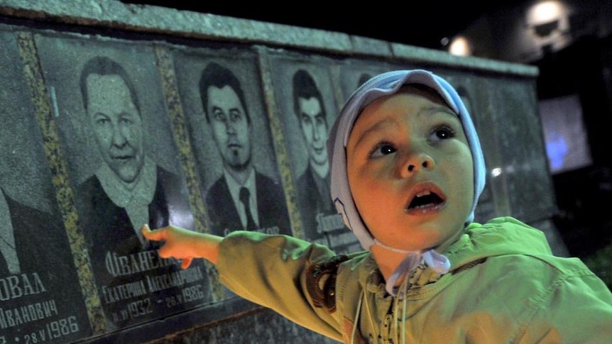 A boy points to his grandmother's portrait in the Chernobyl victims' monument in Slavutich.
