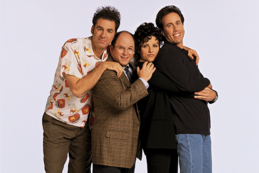 A picture of the Seinfeld cast, arms on each other's shoulders, leaning on one another, looking happy