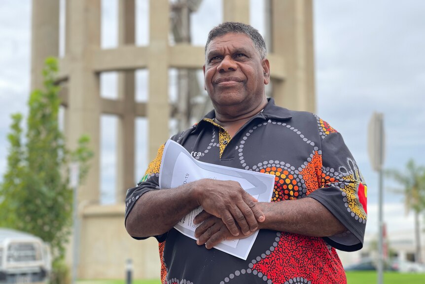 An Indigenous man looks into the distances and clutches a piece of paper before getting his covid vaccine.