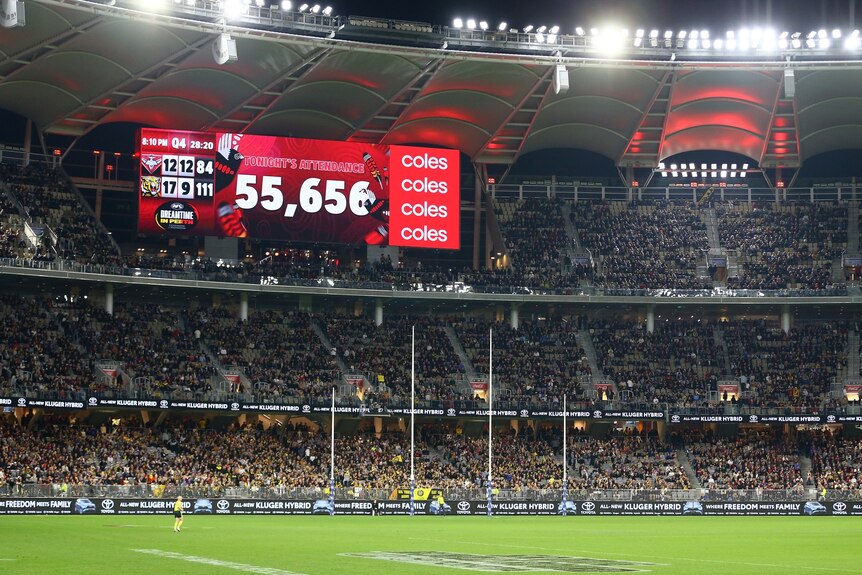 A tall sport stadium full of patrons, with a large screen showing the number of attendees at 55,656.