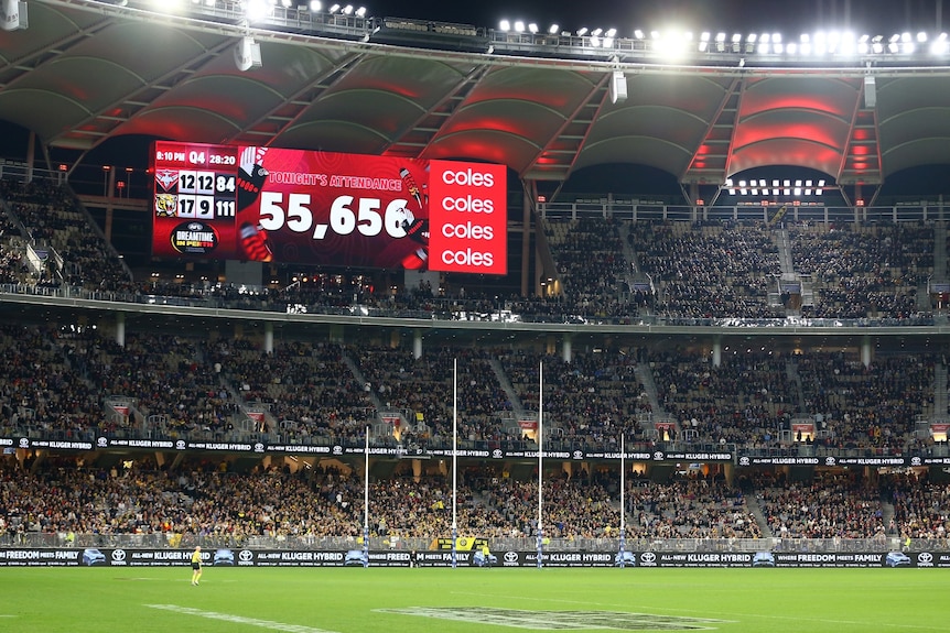 A tall sport stadium full of patrons, with a large screen showing the number of attendees at 55,656.