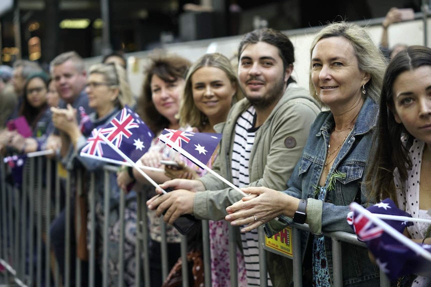 people along a barricade with mini australian flags