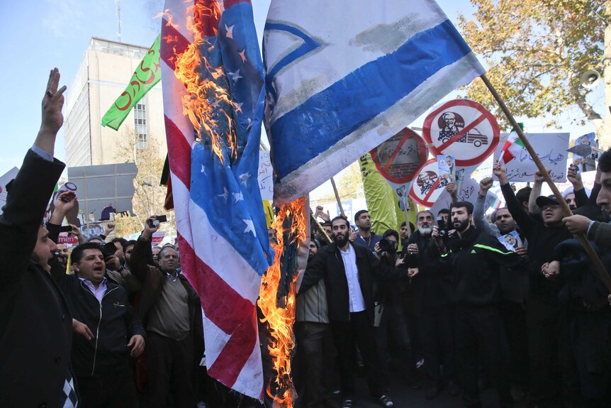 Demonstrators in Iran burn US and Israeli flags.