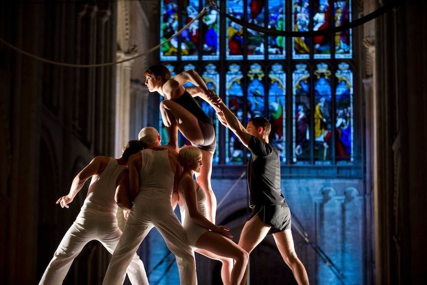 Circus company Circa performing in a cathedral, one acrobat climbing onto a group of acrobats
