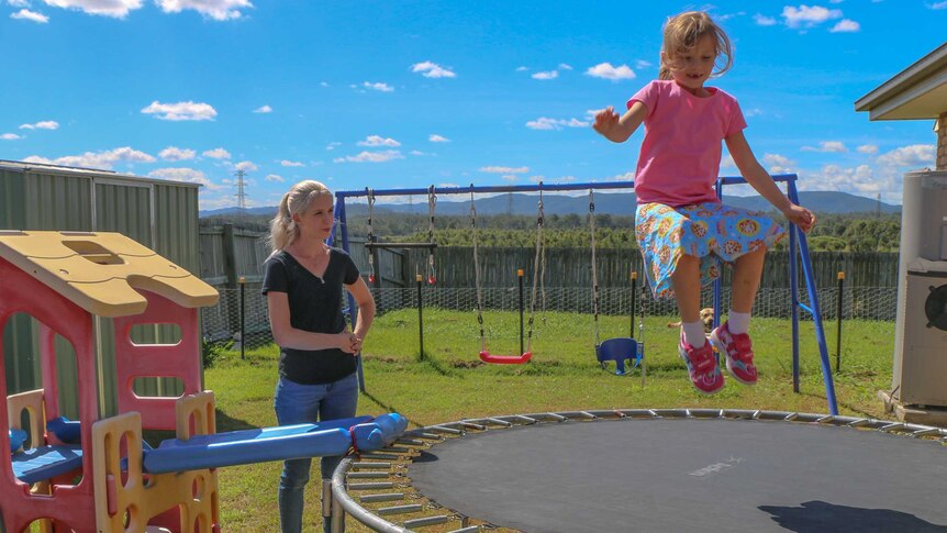 Felicity jumps on the trampoline while her mum Emma watches on.