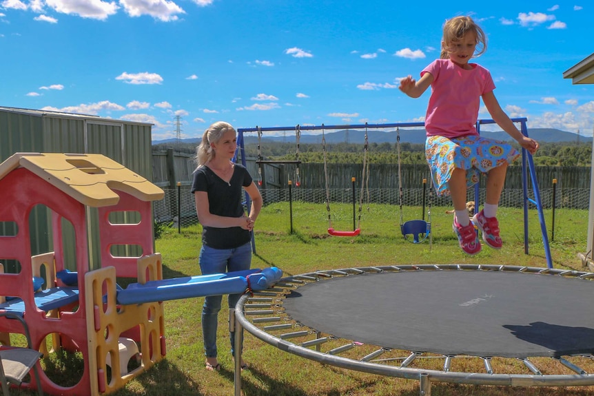 Felicity jumps on the trampoline while her mum Emma watches on.