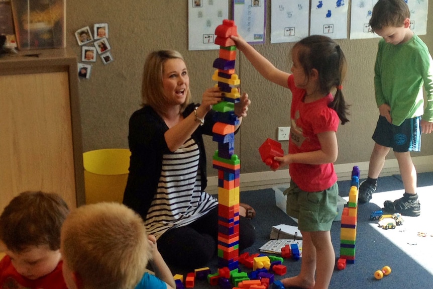 Woman supervising children as they play with blocks at childcare centre.