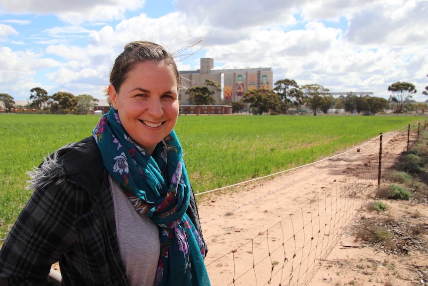 Renee Manning standing near a dirt road, with the painted silos in the far background.