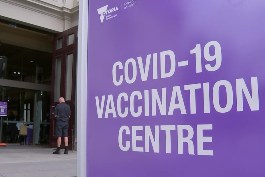 A purple sign outside a building which says COVID-19 vaccination centre.