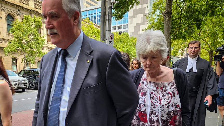 People leave a court in Melbourne, with Frances Walshe looking downcast as she walks behind her lawyer.