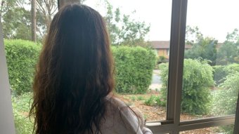A picture of an unidentified woman looking looking out of a window.
