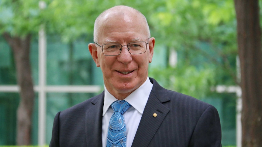 Governor Hurley smiles as he poses for photos in one of the courtyards of Parliament House in Canberra.