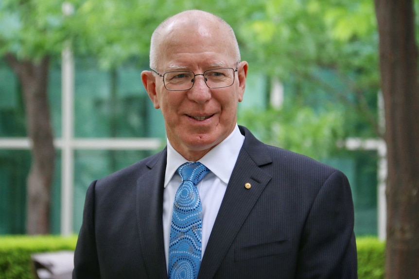 Governor Hurley smiles as he poses for photos in one of the courtyards of Parliament House in Canberra.