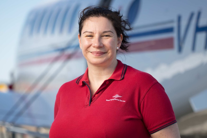 Lady in a red t-shirt in front of a plane.