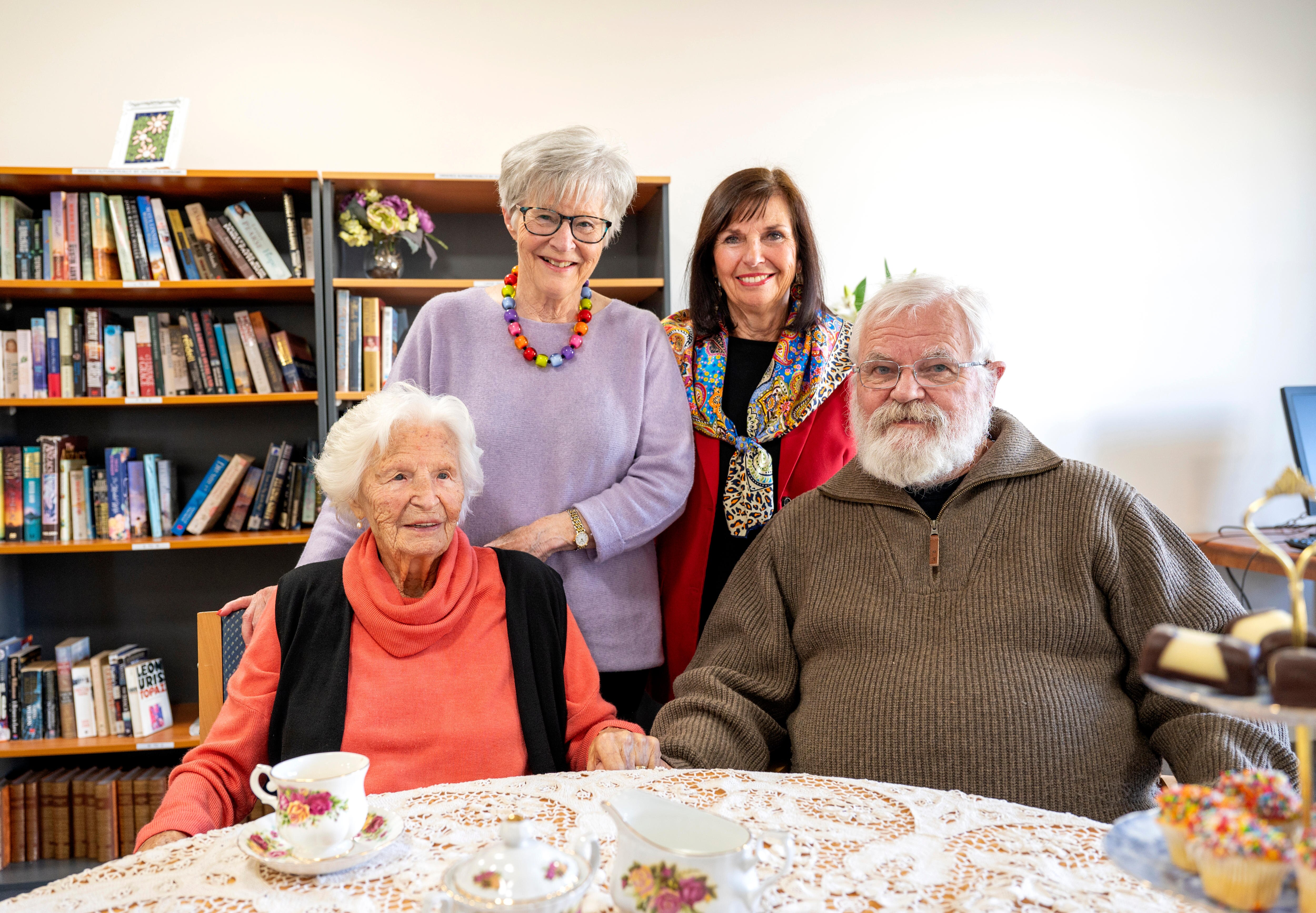 An elderly woman sitting at a table with her two daughters and her son. 