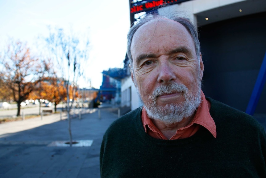 Ian McAuley stands with a billboard in the background at the National Convention Centre in Canberra.
