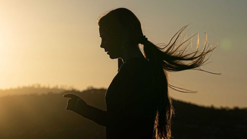A woman, silhouetted, running.