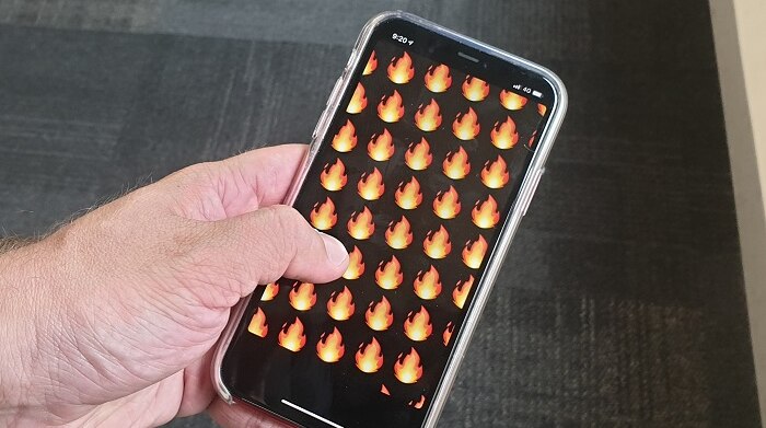 Someone holding a phone with flame emojis on the screen