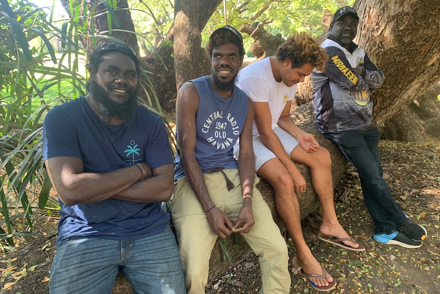 Four men sitting and standing together.