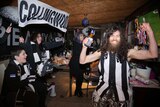 Passionate fans jump and cheer while watching a Collingwood match from home