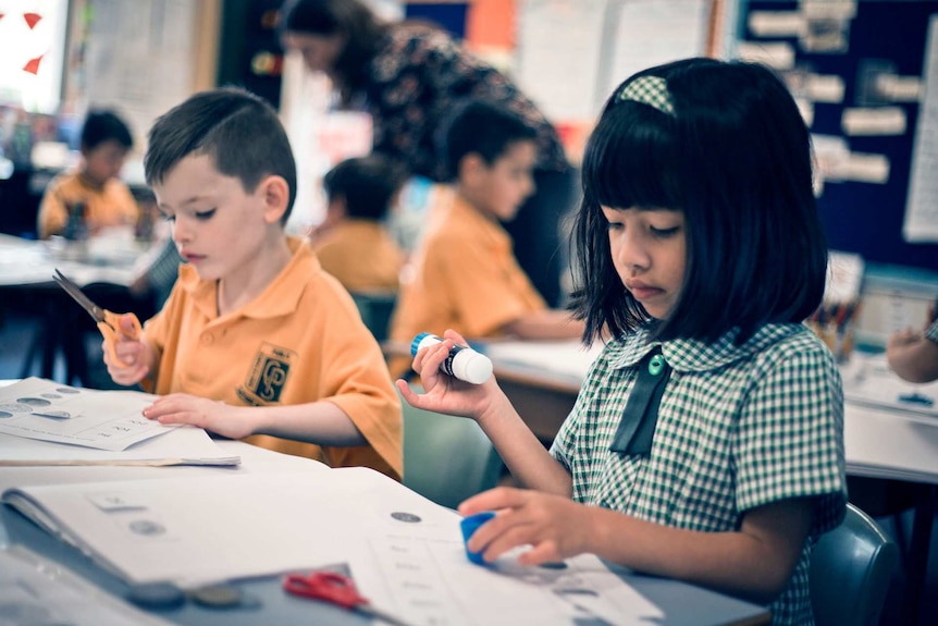 Photo of primary school students cutting and pasting