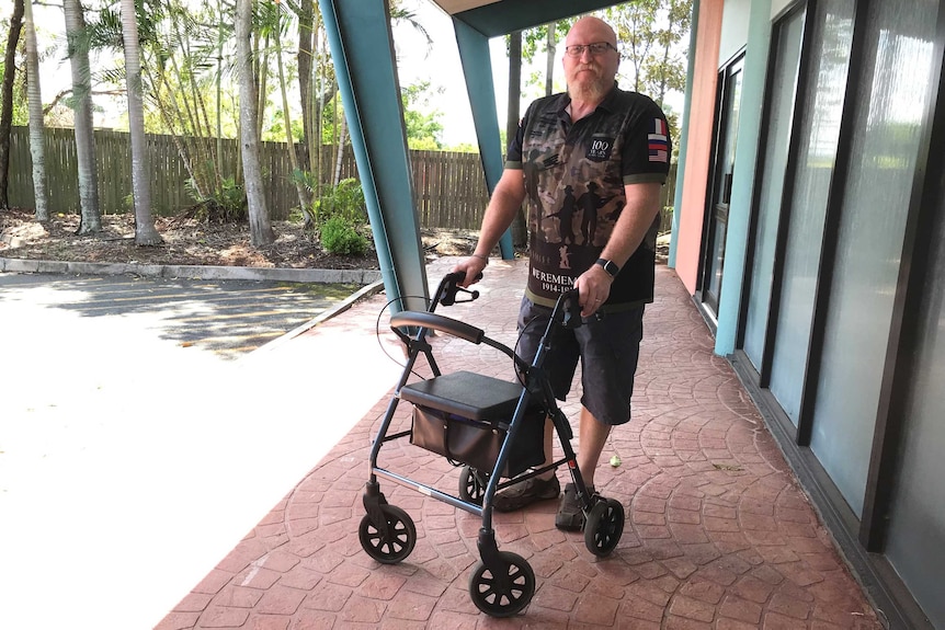 Scott Harris stands with a walking frame