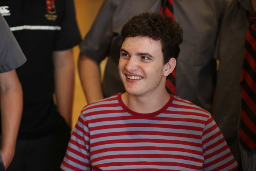 Young man in striped shirt looks up at friends.