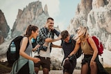 A group of four smiling friends at a canyon setting on a holiday for a story about what travel insurance doesn't cover.