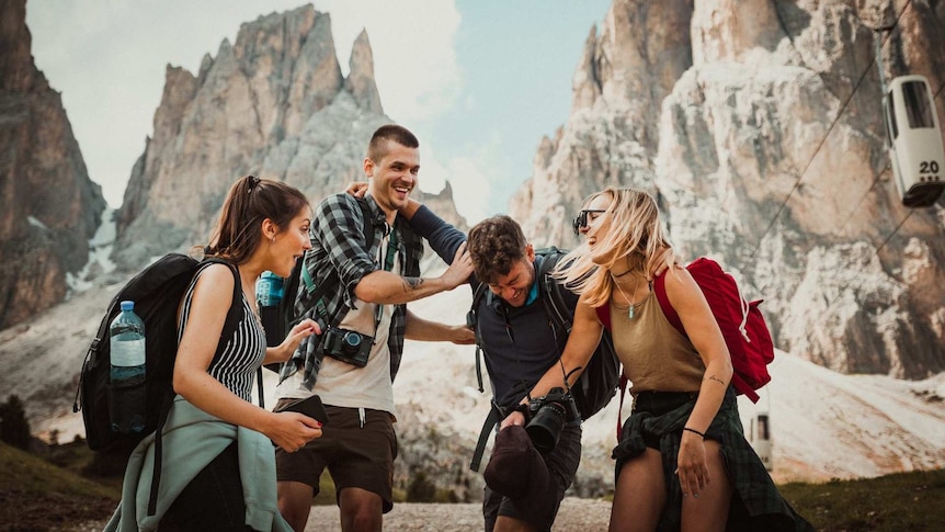 A group of four smiling friends at a canyon setting on a holiday for a story about what travel insurance doesn't cover.