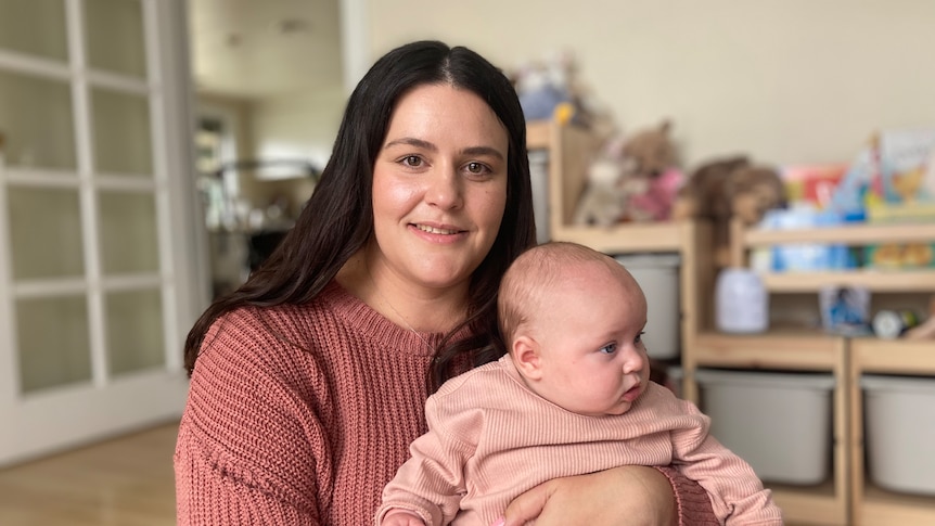 A smiling woman holds her baby.