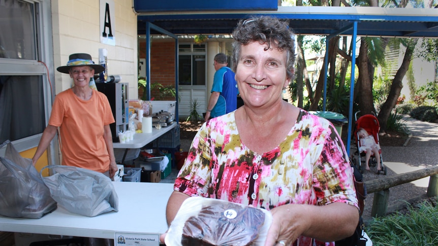 Anne Davis smiling holding a try of muffins.