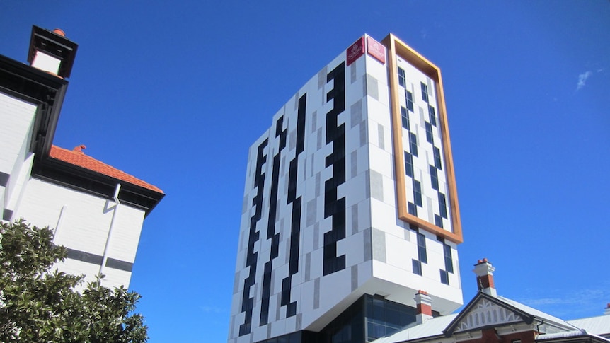A modern multi-storey building stands next to a heritage building.