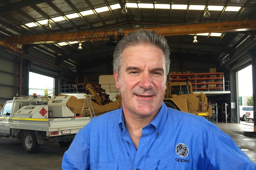A picture of Matt Doman wearing a blue shirt in a machinery workshop.