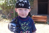 A young boy with a pirate bandana and a skull and cross bones T-shirt.