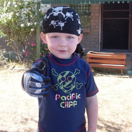 A young boy with a pirate bandana and a skull and cross bones T-shirt.