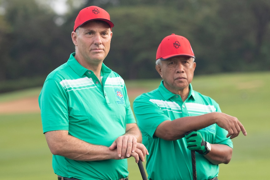 Richard Marles stands on a golf course holding a club in cambodia 